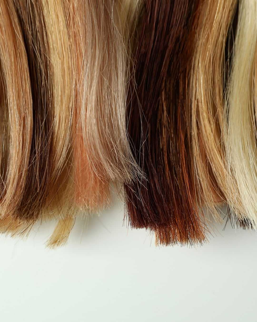 Variety of hair extensions in different blonde and brown shades against a white background.