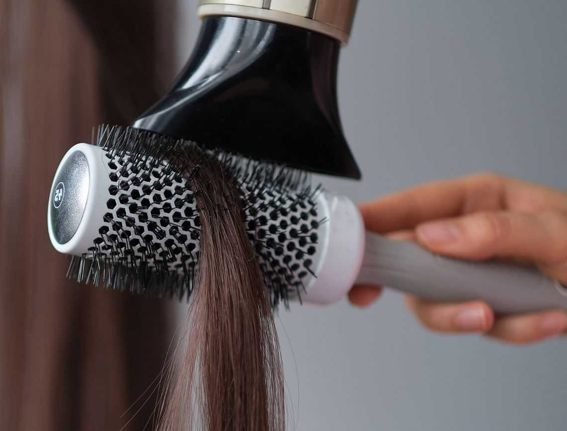 Blow-drying hair with a round brush for smooth styling.
