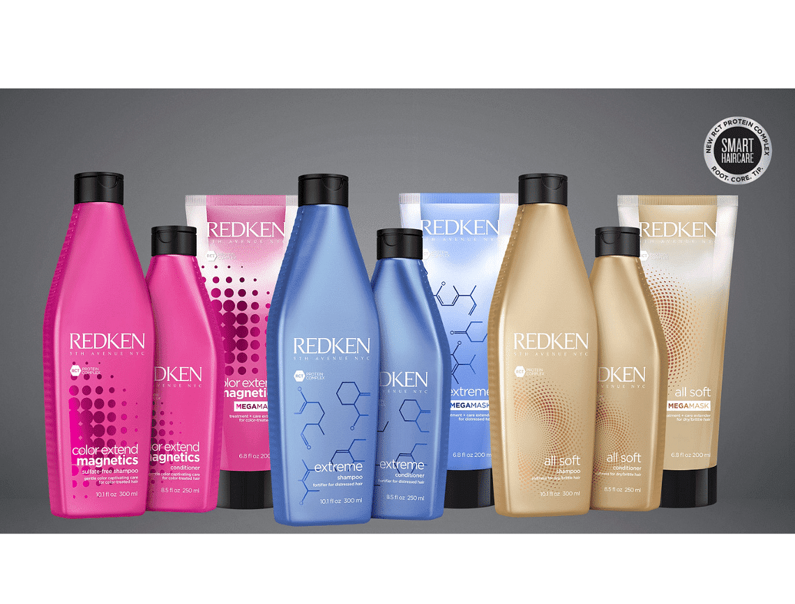 Redken hair products in various bottles and tubes, arranged on a gray background.